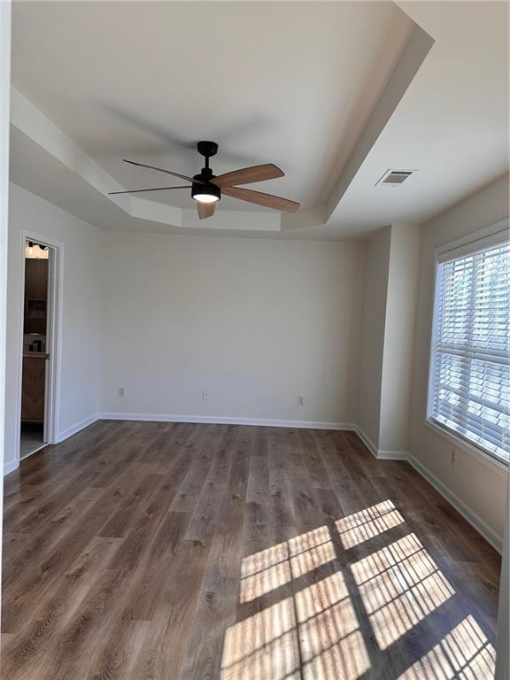 spare room featuring dark wood-type flooring, ceiling fan, and a tray ceiling