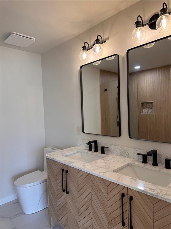 bathroom featuring walk in shower, vanity, and toilet