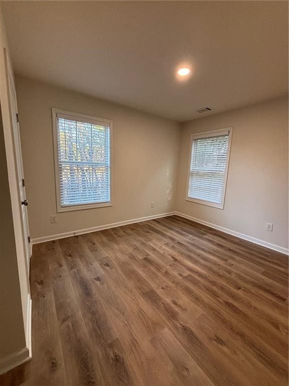 empty room featuring dark wood-type flooring and a healthy amount of sunlight