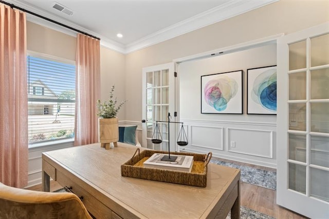 office area with visible vents, wood finished floors, a decorative wall, wainscoting, and crown molding