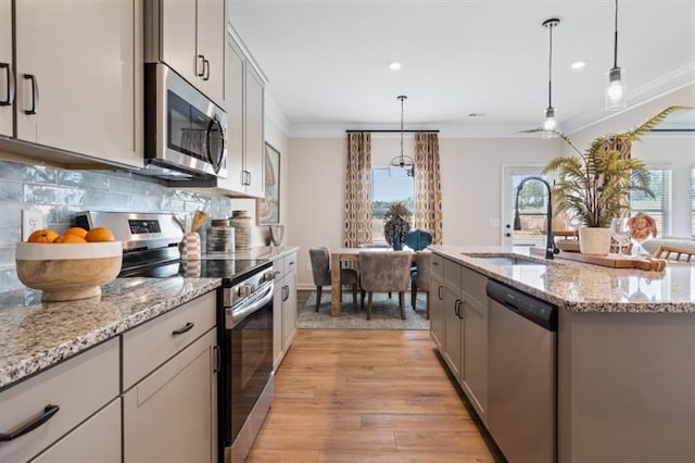 kitchen featuring crown molding, decorative backsplash, gray cabinets, appliances with stainless steel finishes, and a sink