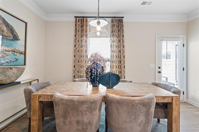 dining area featuring a healthy amount of sunlight, crown molding, and wood finished floors