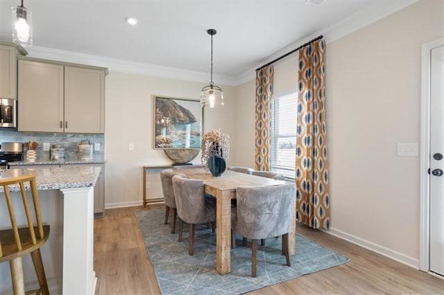 dining room with baseboards, light wood-style floors, and ornamental molding