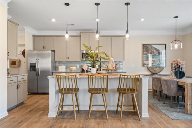 kitchen featuring decorative backsplash, a kitchen island, appliances with stainless steel finishes, and light wood-style flooring