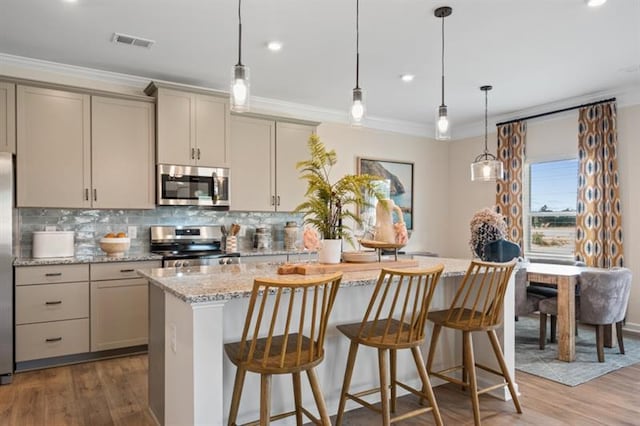 kitchen featuring visible vents, gray cabinetry, ornamental molding, stainless steel appliances, and decorative backsplash