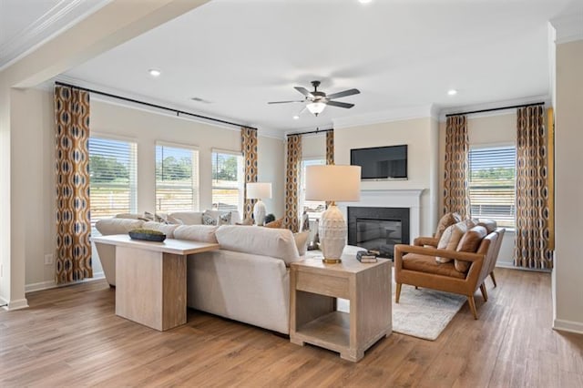 living area with light wood-style flooring, plenty of natural light, and ornamental molding