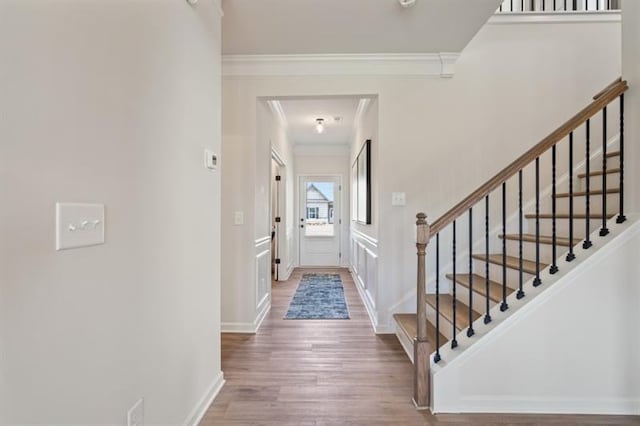 entrance foyer featuring crown molding, stairway, wood finished floors, and baseboards