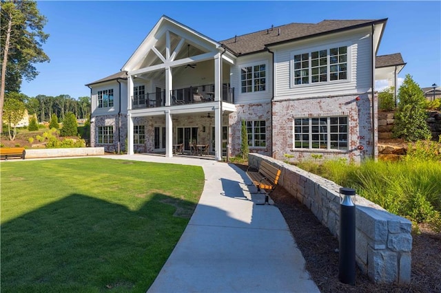 back of property with a balcony, a patio area, ceiling fan, and a lawn