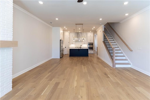 unfurnished living room featuring crown molding, light hardwood / wood-style floors, and sink