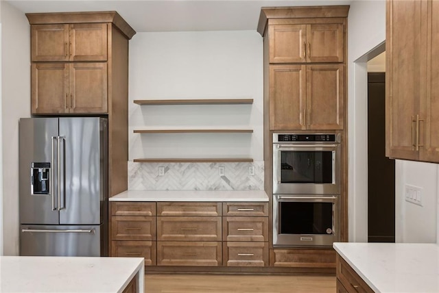 kitchen with light wood-type flooring, appliances with stainless steel finishes, and backsplash