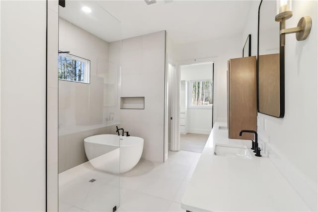 bathroom featuring tile patterned flooring, a healthy amount of sunlight, a bathtub, and vanity