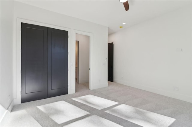 unfurnished bedroom with ceiling fan, a closet, and light carpet