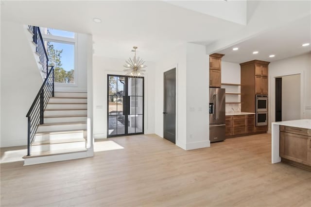 kitchen featuring an inviting chandelier, hanging light fixtures, light wood-type flooring, stainless steel appliances, and french doors