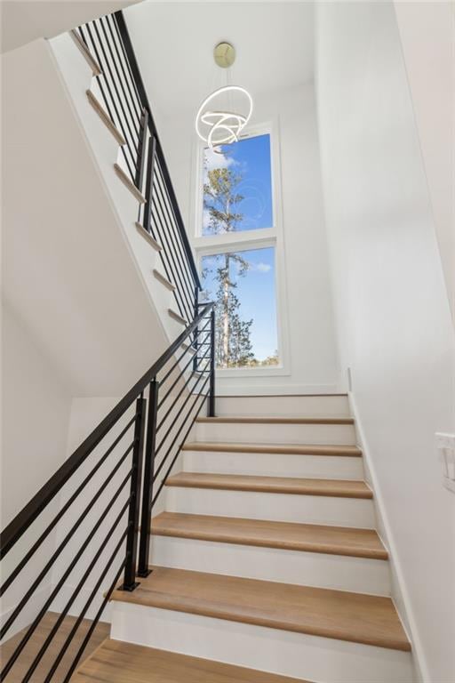 stairway featuring hardwood / wood-style flooring and an inviting chandelier