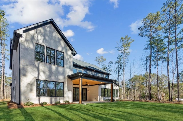 back of house with ceiling fan, a yard, and a patio