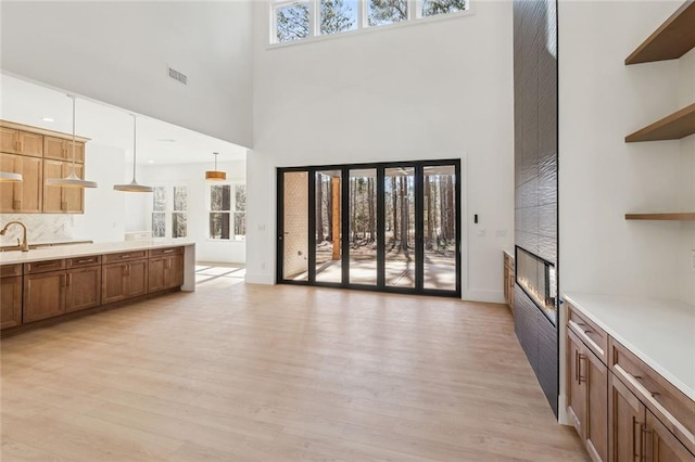 living room with light wood-type flooring, a towering ceiling, and sink