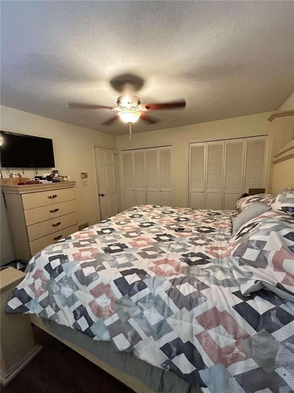 bedroom featuring a textured ceiling, ceiling fan, and multiple closets