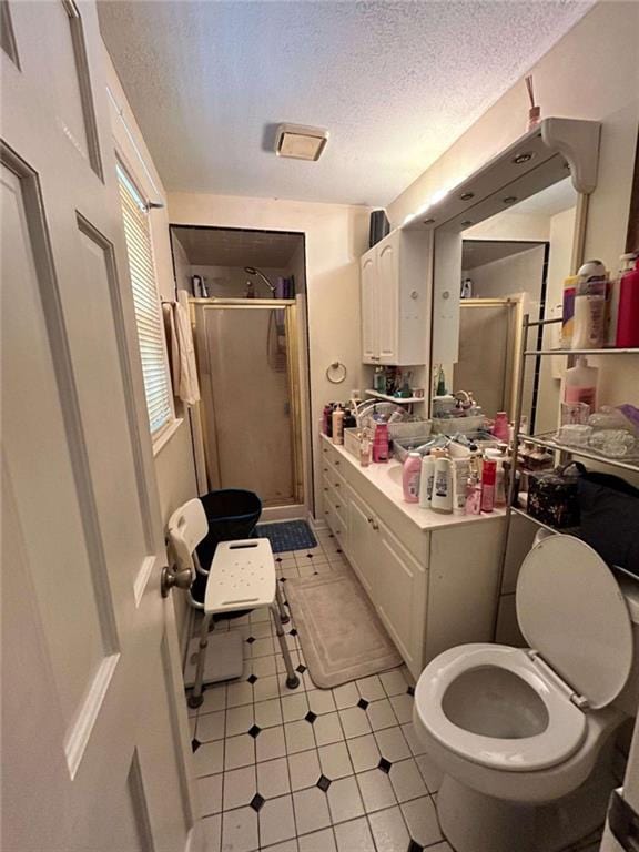 bathroom with a textured ceiling, vanity, toilet, and walk in shower