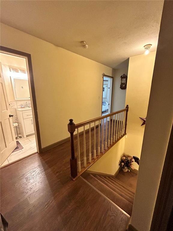 staircase with a textured ceiling, hardwood / wood-style flooring, and sink