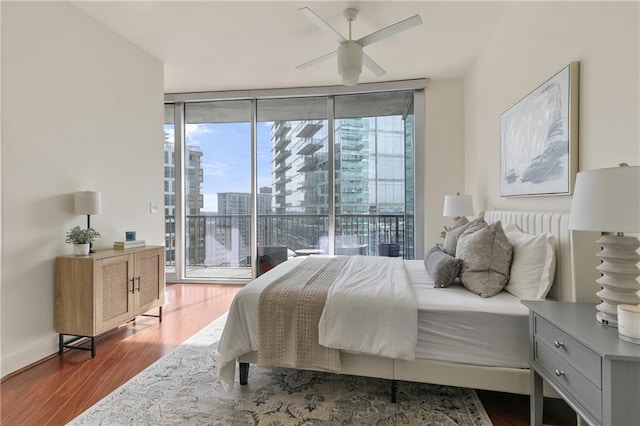 bedroom with expansive windows, ceiling fan, access to exterior, and hardwood / wood-style flooring