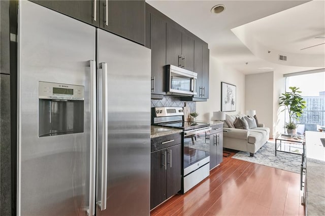 kitchen with tasteful backsplash, hardwood / wood-style flooring, ceiling fan, and appliances with stainless steel finishes