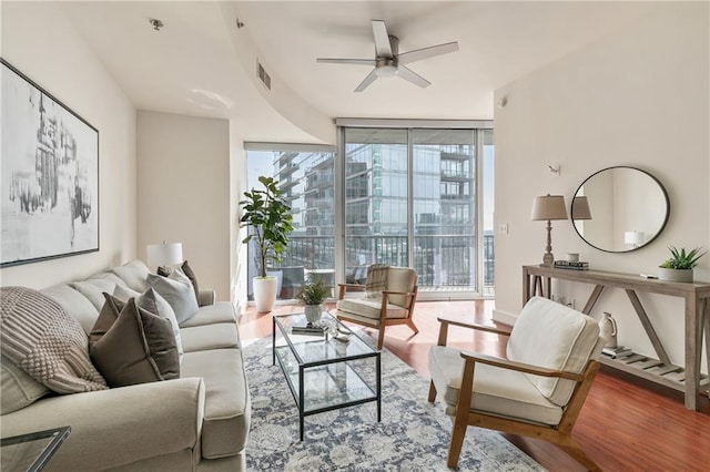 living room with expansive windows, hardwood / wood-style flooring, and ceiling fan