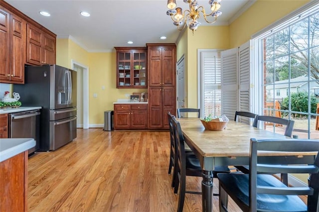 dining room with light wood-style flooring, a notable chandelier, baseboards, and ornamental molding