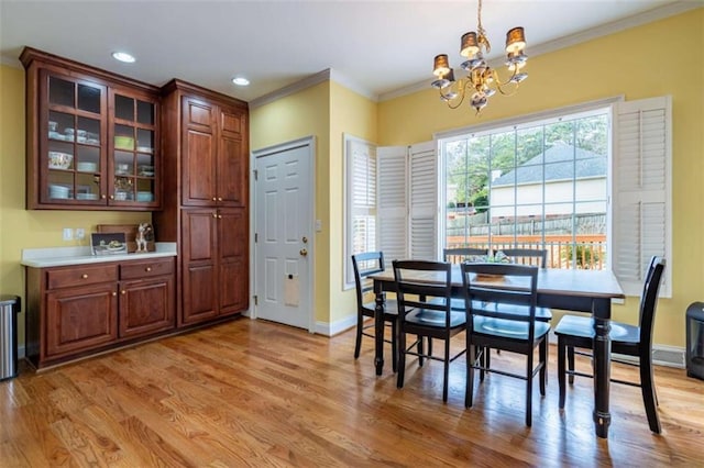 dining space featuring a notable chandelier, light wood-type flooring, baseboards, and ornamental molding