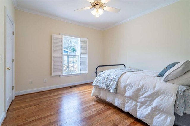 bedroom featuring visible vents, baseboards, ornamental molding, wood finished floors, and a ceiling fan