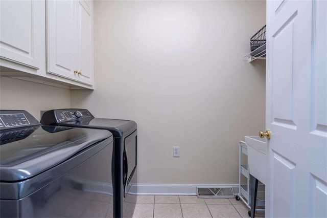 laundry room featuring visible vents, cabinet space, separate washer and dryer, light tile patterned floors, and baseboards