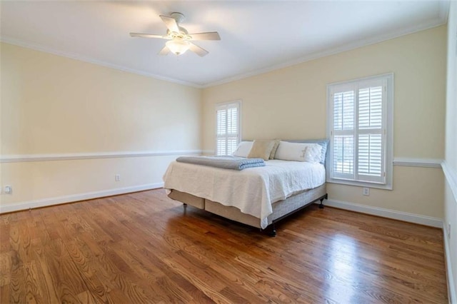 bedroom featuring ceiling fan, baseboards, wood finished floors, and crown molding