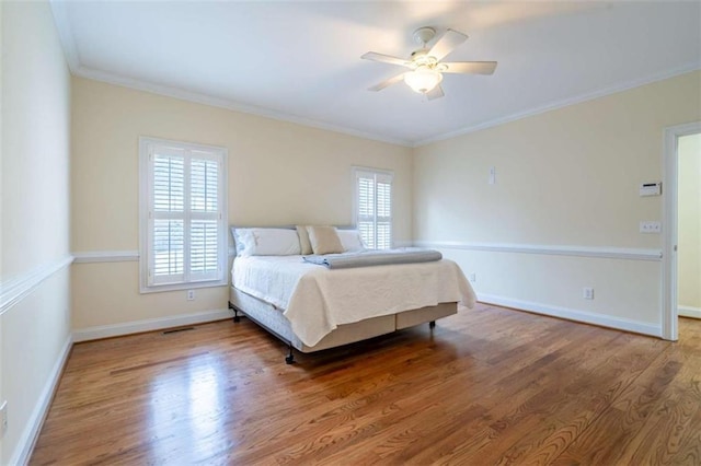 bedroom featuring ornamental molding, a ceiling fan, baseboards, and wood finished floors