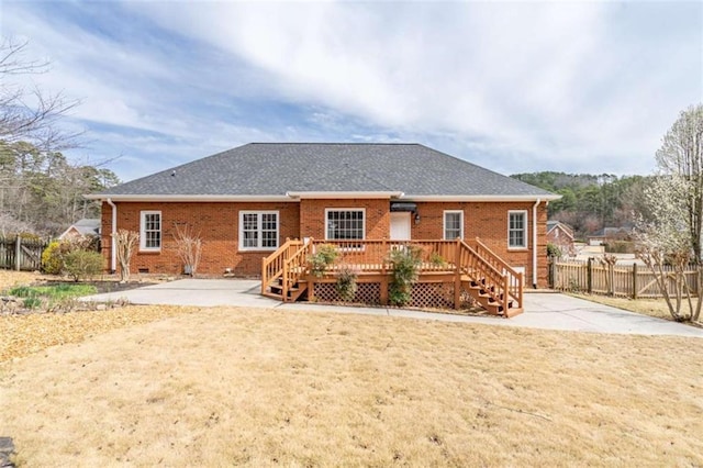 back of house with a lawn, fence, roof with shingles, crawl space, and brick siding