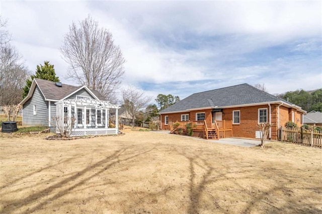 back of house featuring cooling unit, brick siding, a deck, and fence