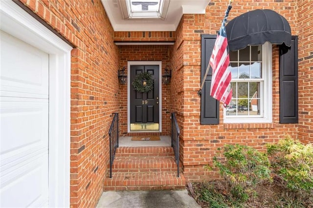 view of exterior entry featuring an attached garage and brick siding