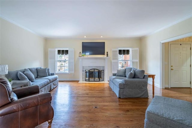 living room featuring a glass covered fireplace, baseboards, wood finished floors, and crown molding