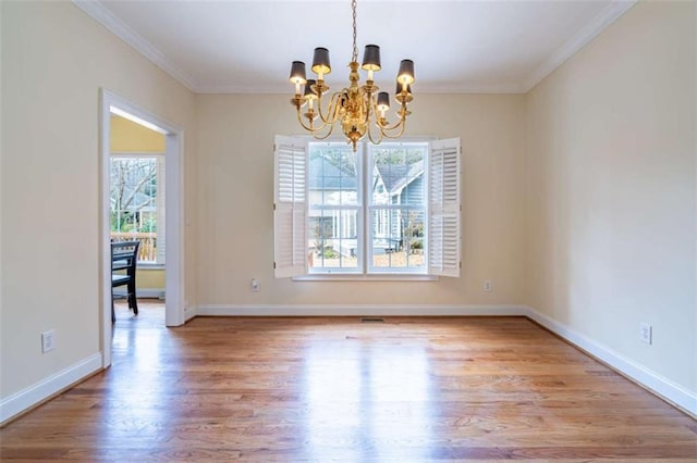 unfurnished dining area featuring baseboards, an inviting chandelier, wood finished floors, and crown molding