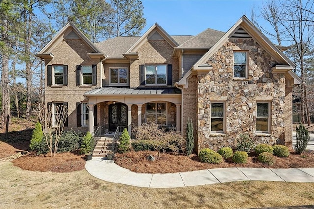 view of front of home with stone siding, roof with shingles, a porch, and brick siding