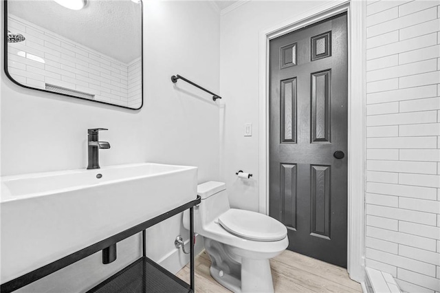 bathroom featuring crown molding, toilet, hardwood / wood-style flooring, and a shower