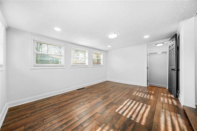 empty room featuring a textured ceiling and dark hardwood / wood-style flooring