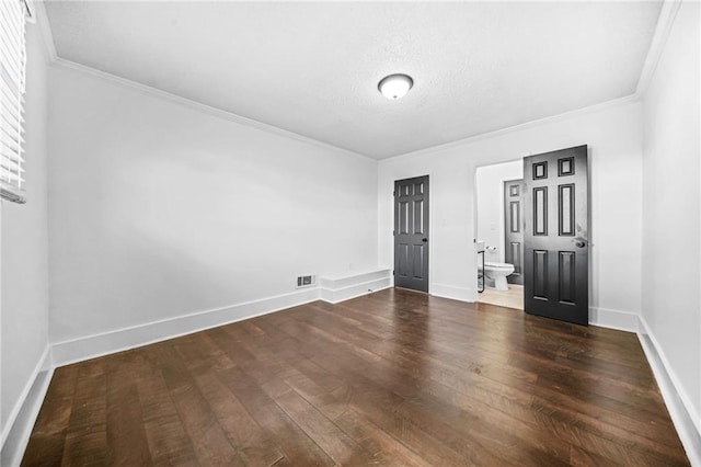 empty room with crown molding, dark wood-type flooring, and a textured ceiling