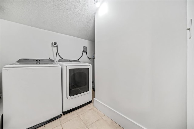 laundry room with a textured ceiling, light tile patterned floors, and washing machine and clothes dryer