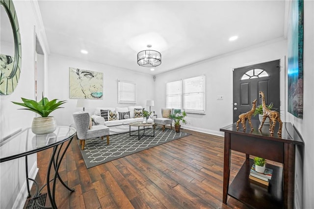 living room with dark wood-type flooring, crown molding, and a chandelier