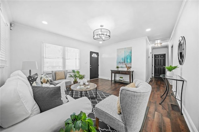 living room featuring dark hardwood / wood-style flooring, crown molding, and an inviting chandelier