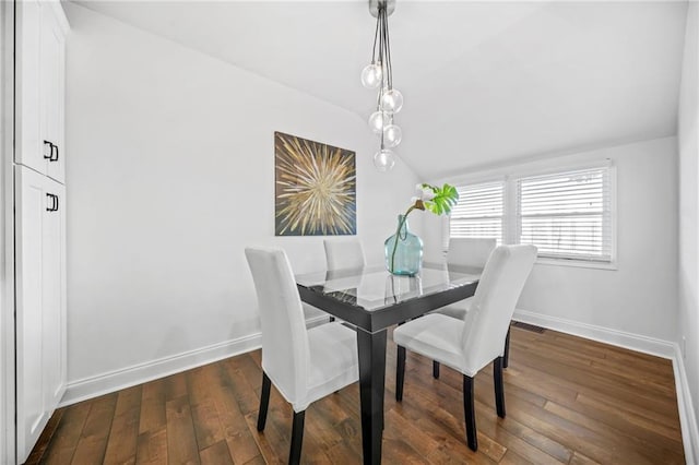 dining area featuring vaulted ceiling and dark wood-type flooring