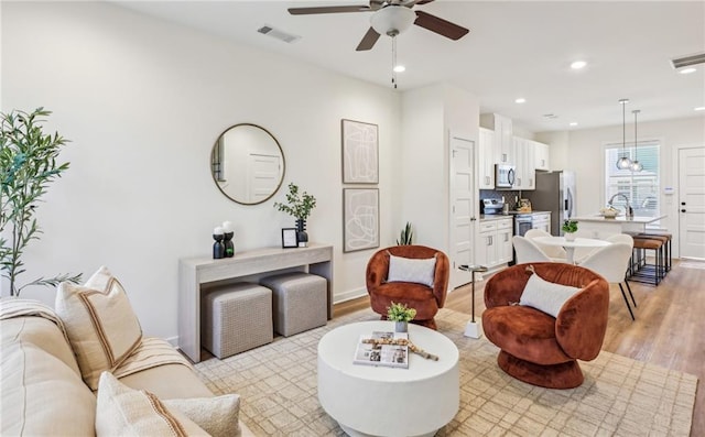 living room featuring ceiling fan, recessed lighting, visible vents, and light wood-style floors