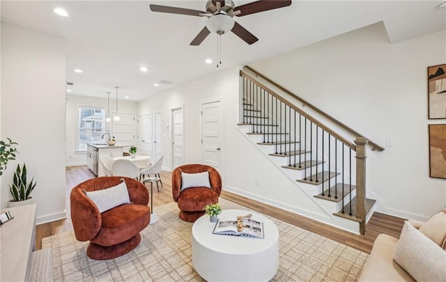 living area with light wood-style floors, recessed lighting, stairway, and baseboards