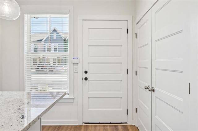 doorway to outside with light wood-type flooring and baseboards