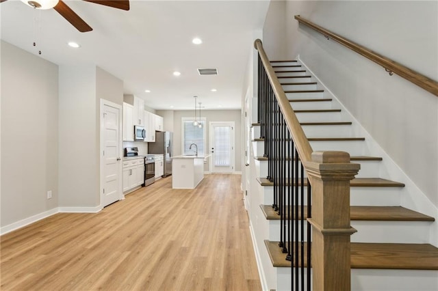 stairs with ceiling fan, sink, and hardwood / wood-style floors