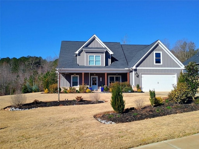 craftsman-style house with board and batten siding, a front yard, a garage, and driveway